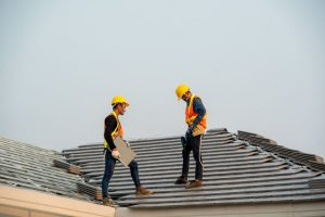 Two workers stand on a roof