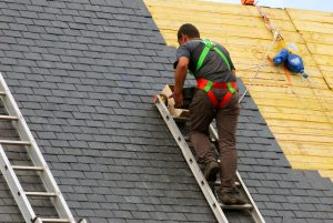 A roofer works on a slate roof.