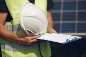 A worker holds a hard hat and clipboard