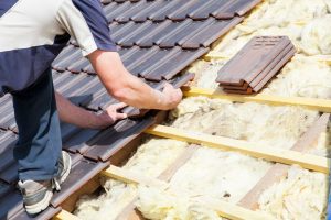 A worker places tiles on a roof