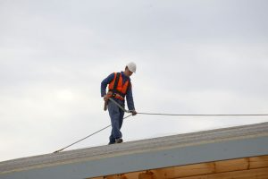 A roofer stands on a roof
