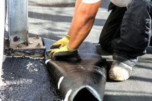 A worker lays down part of a flat roof.