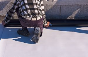 A worker places a single ply roofing system.