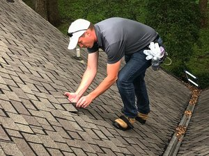A worker inspects roof shingles