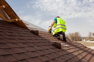 A man works on an Asphalt Shingle roof