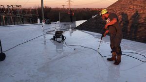 A worker applies EPDM to a commercial roof