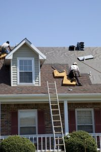 Roofers work on a shingle roof