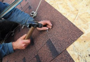 A roofer places shingles