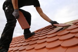 A worker replaces roof tiles