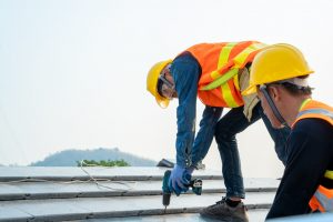 Two roofers work on a roof