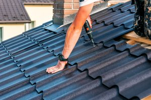 A roofer works on a metal roof