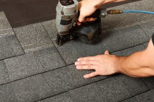 A worker places asphalt shingles