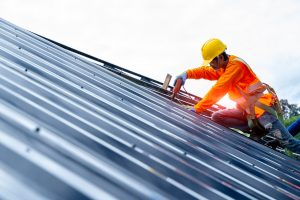 A roofer works on a metal roof