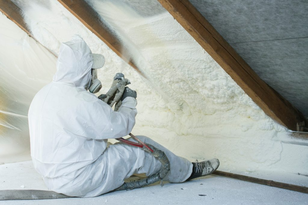 A worker sprays polyurethane foam in an attic